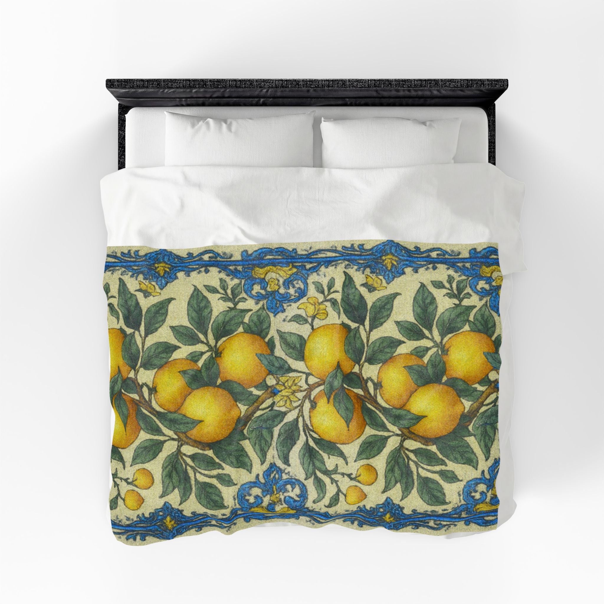 A plush velveteen blanket with an orange and blue botanical pattern spread over a white bed with a black headboard, top-down view.