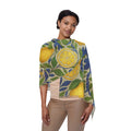 A woman wearing a lightweight semi-translucent scarf with a bright lemon and blue flower botanical print, draped over her shoulders.