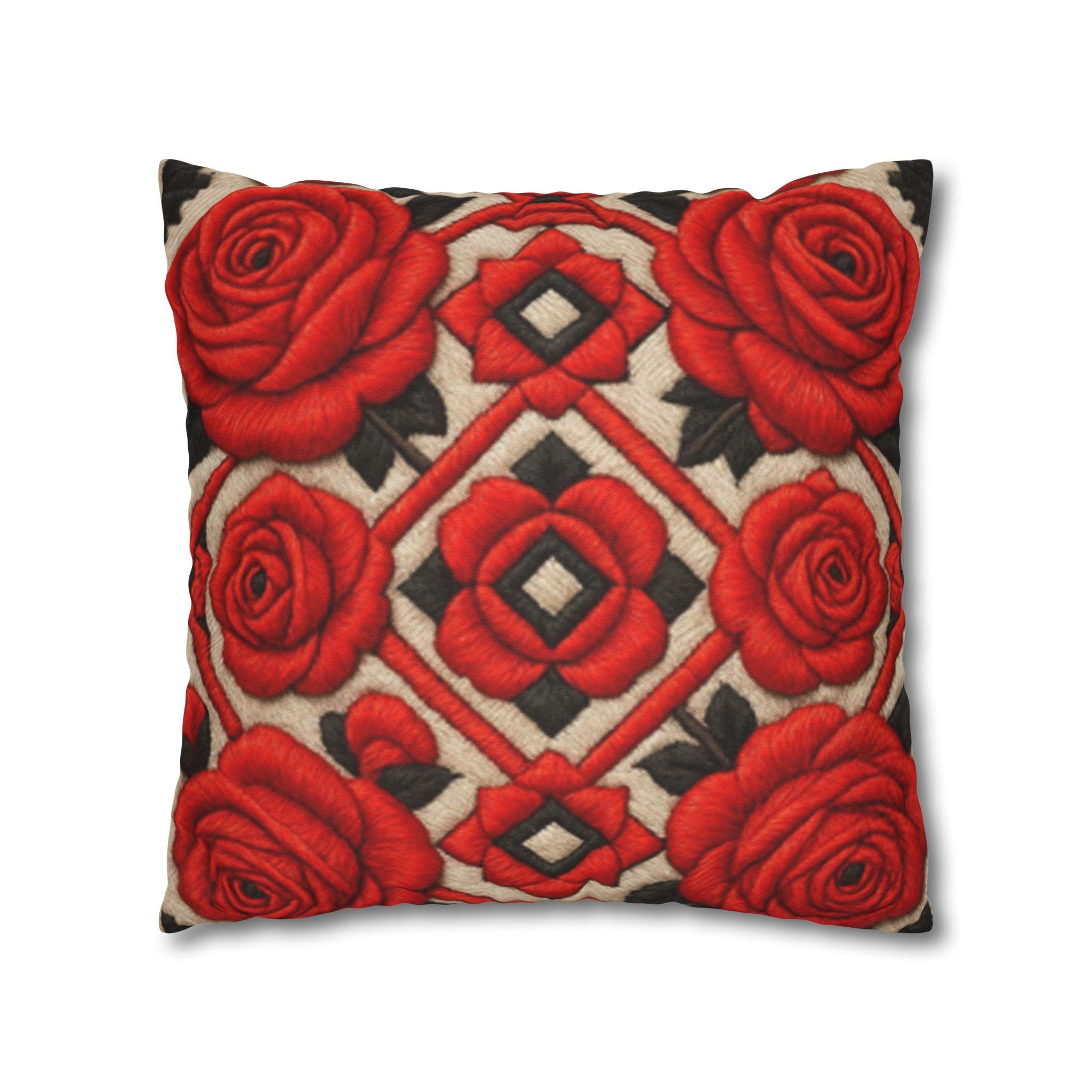 A square throw pillow with a red rose and geometric pattern sitting on a grey fabric couch next to a houseplant.