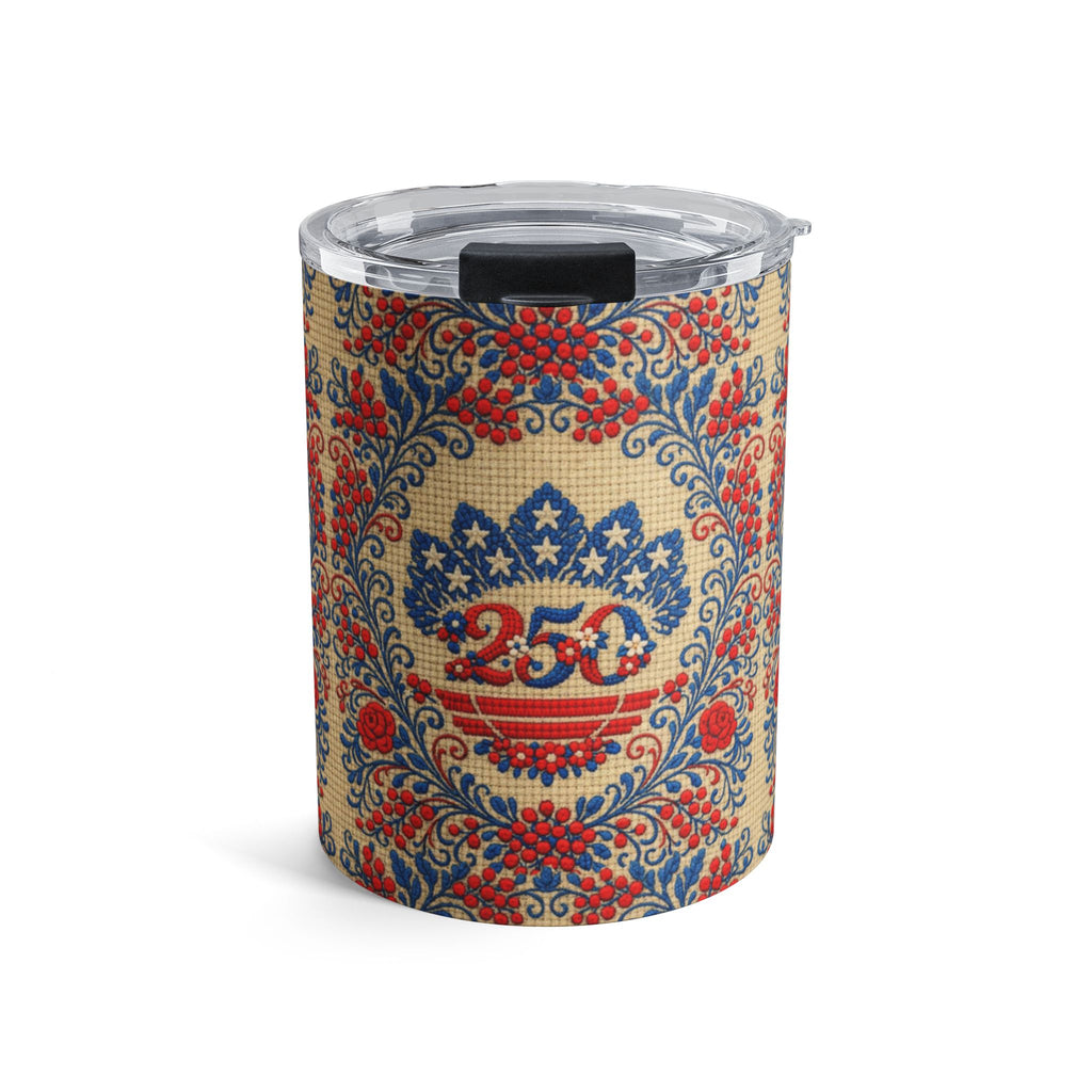 A 10oz stainless steel travel tumbler with a clear lid, featuring the "Freedom's Garden 250" design. The pattern displays a vintage-style red and blue 250 anniversary shield and floral folk art motifs on a soft cream-colored background.