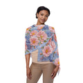 A woman wearing a lightweight Soft Provence scarf with a pink peony and blue hydrangea floral pattern, draped elegantly over her shoulders.