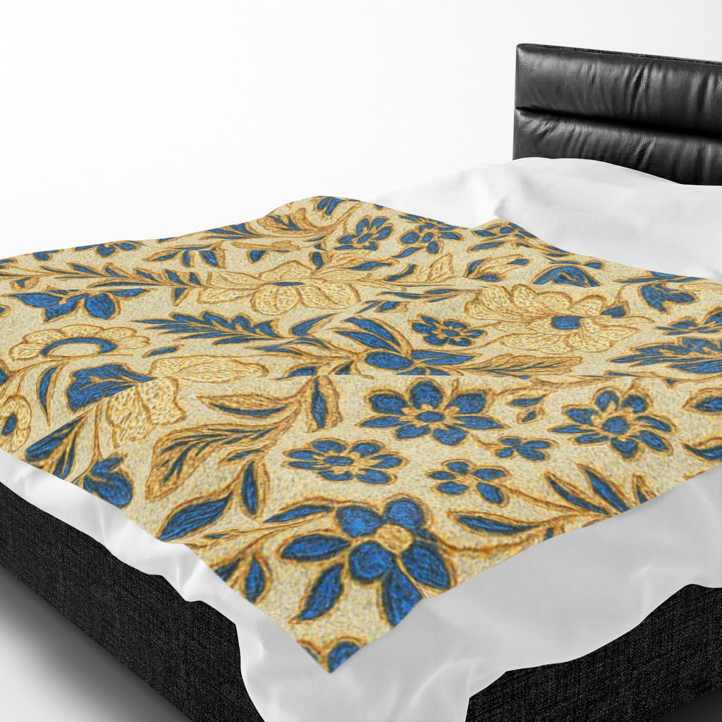 Velveteen plush blanket featuring a William Morris inspired floral pattern with intricate gold flowers and teal blue leaves on a cream background, styled on a modern bed.
