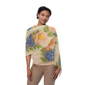 A woman wearing a lightweight scarf from the Wooly Garden collection with a pink daisy and blue hydrangea print featuring a 3D wool embroidery effect.