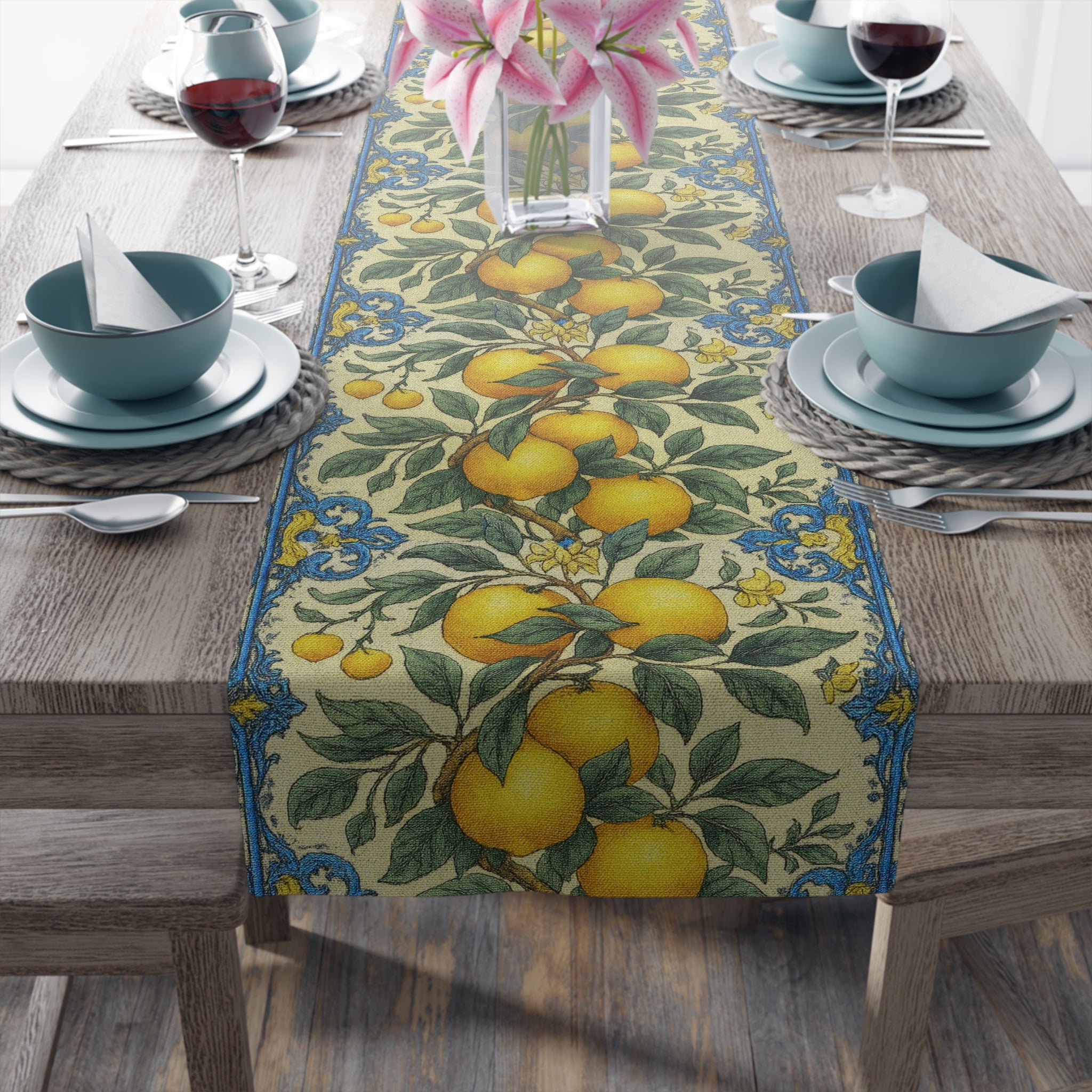 Mediterranean style table runner with lemon and orange vine pattern, blue ornamental borders, on a wooden dining table with blue plates and wine glasses.