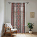 Vertical sheer window curtain from the Stasia Red Collection featuring red and grey Slavic folk embroidery patterns, filtering sunlight in a cozy room.